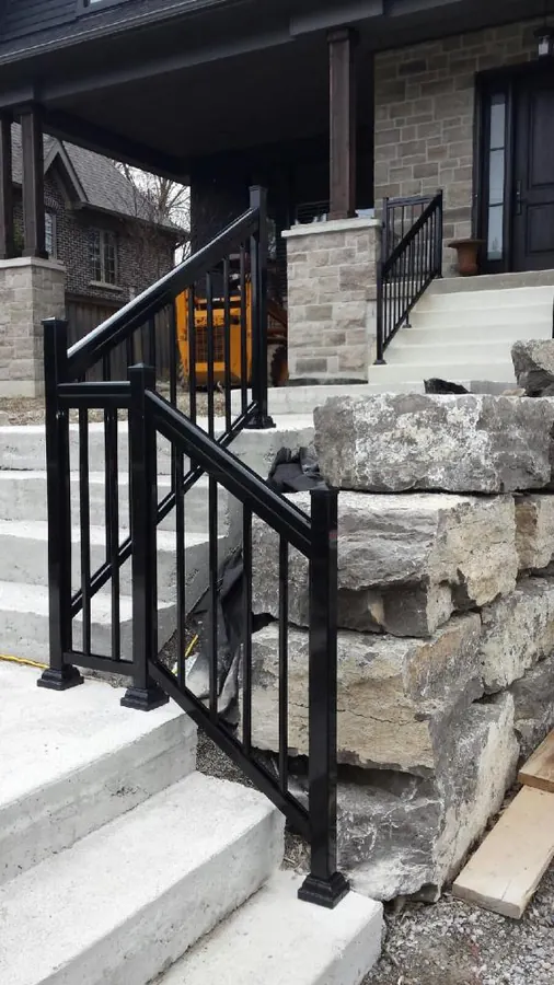 Black aluminum picket railing on stone-step entry with double-post landing detail