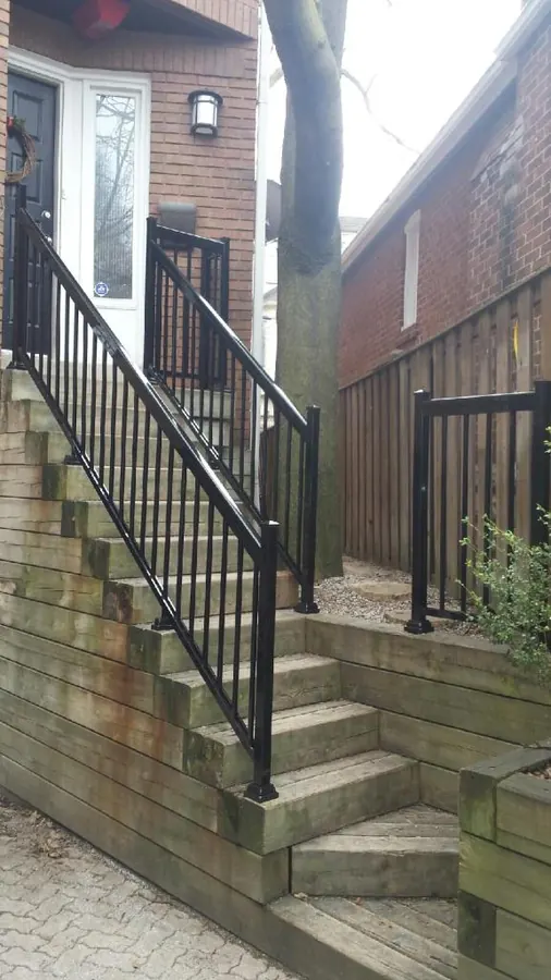 Black aluminum side-stair railing on grey concrete steps with brick exterior