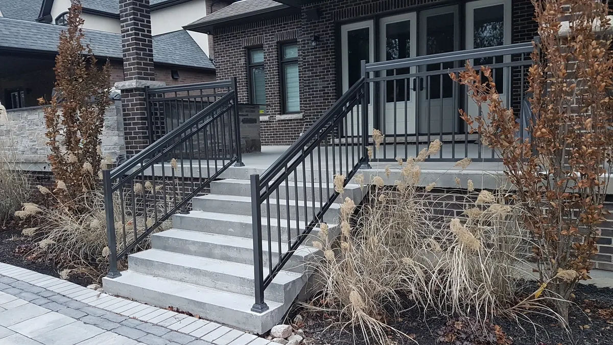 Black aluminum stair railing on stone-trimmed entry with bronze top rail
