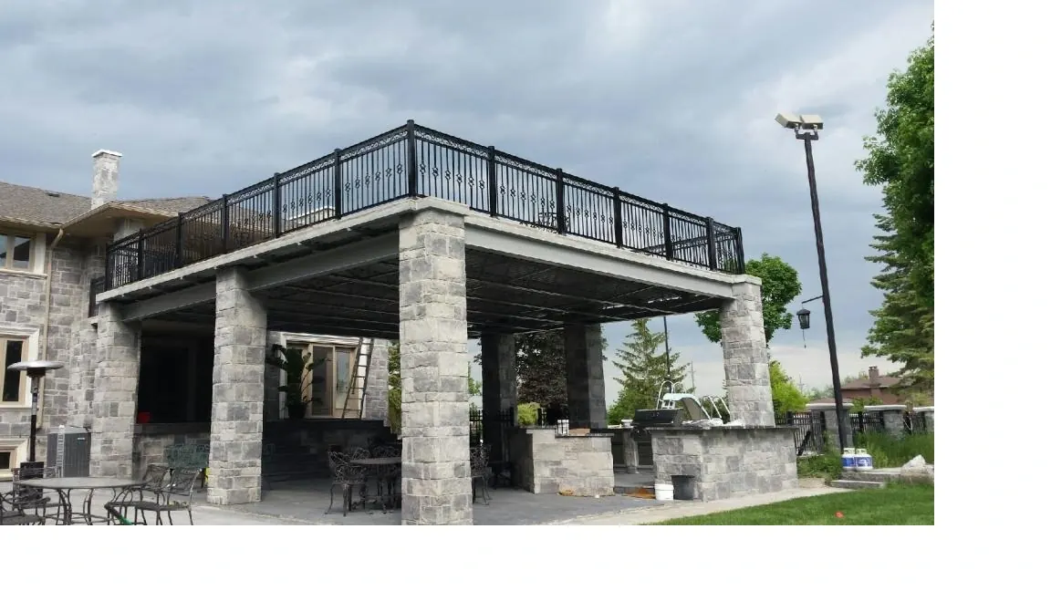 Decorative aluminum rooftop pergola railing with scrollwork over stone columns